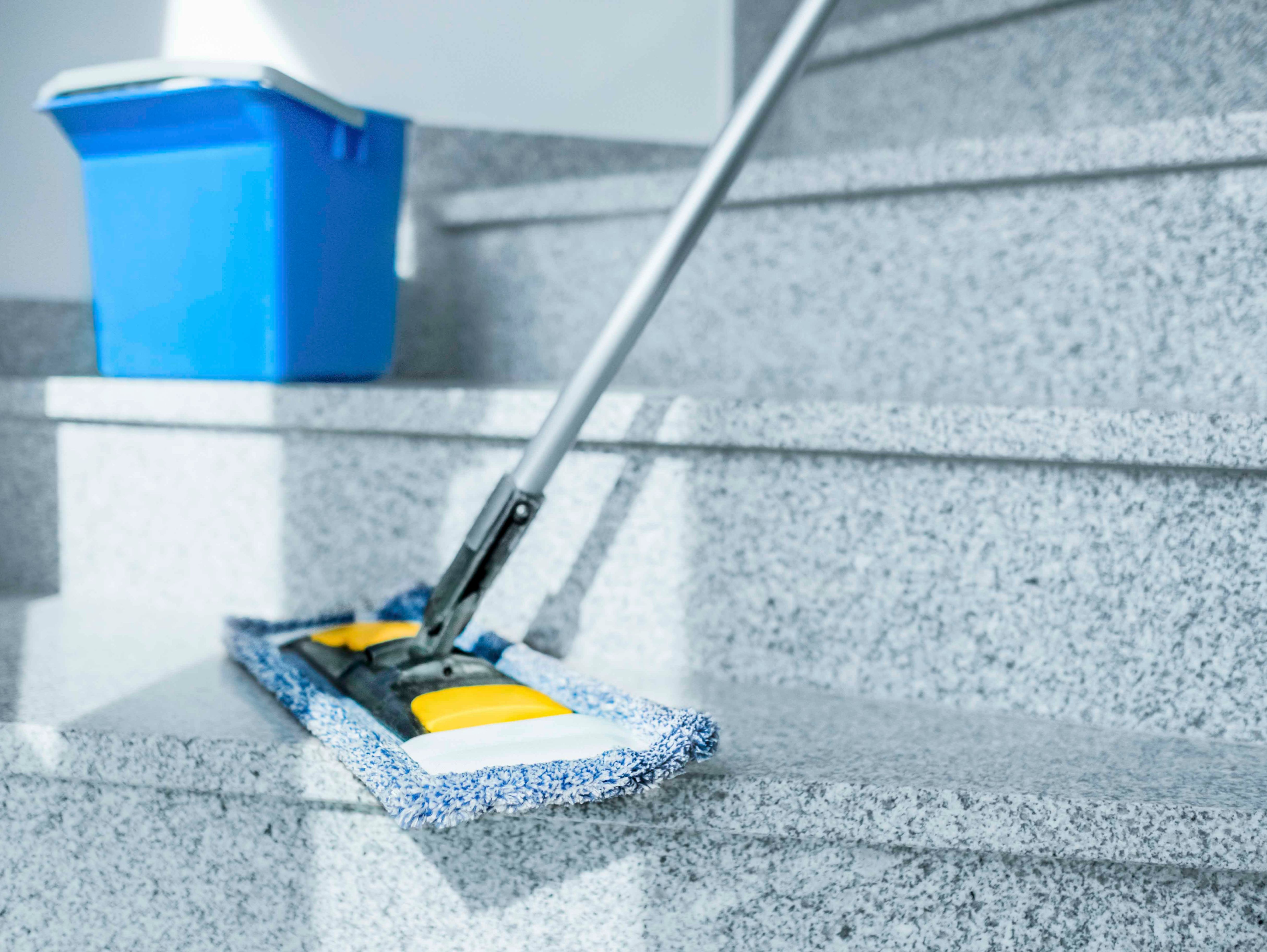 Ein Wischmopp und ein Eimer im hellen Treppenhaus